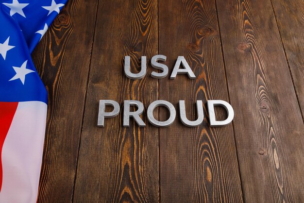 Foto las palabras usa proud colocadas con letras metálicas plateadas en superficie de madera con la bandera de los estados unidos