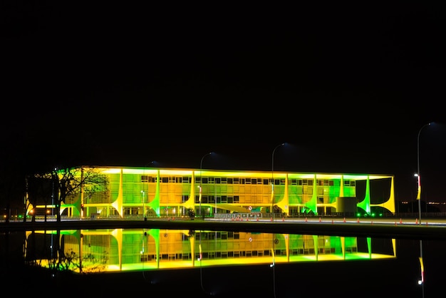 Foto palácio iluminado do planalto refletindo-se na água à noite