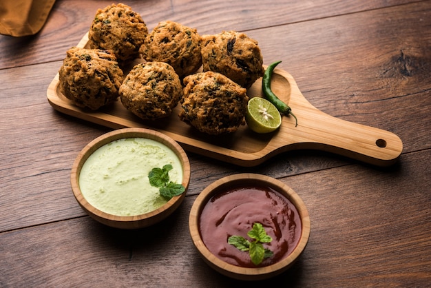 Palak OR Methi Pakora es un bocadillo indio servido con salsa picante de menta verde y salsa roja, enfoque selectivo