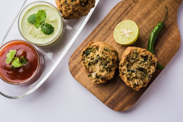 Palak OR Methi Pakora es un bocadillo indio servido con salsa picante de menta verde y salsa roja, enfoque selectivo