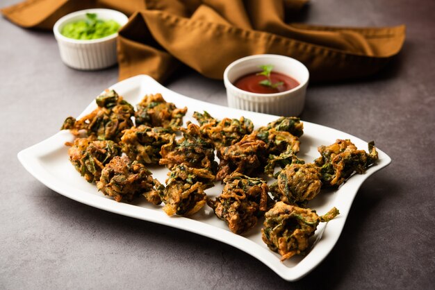 Palak pakoda o pakora sabrosa casera conocida como Spinach Firtters, servida con salsa de tomate. Merienda favorita de la India para la hora del té