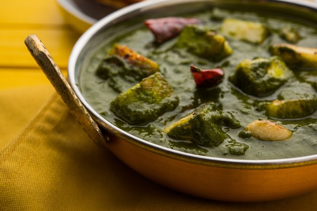 Palak paneer curry aus spinat und hüttenkäse, beliebtes indisches gesundes mittag- oder abendessen, serviert in einem karahi mit roti oder chapati über stimmungsvollem hintergrund. selektiver fokus