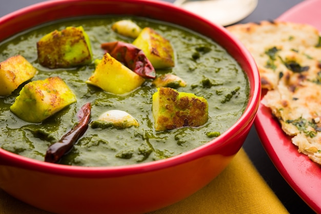 Palak Paneer Curry composto de espinafre e queijo cottage, menu de comida saudável para almoço ou jantar indiano popular, servido em um Karahi com Roti ou Chapati sobre fundo sombrio. foco seletivo