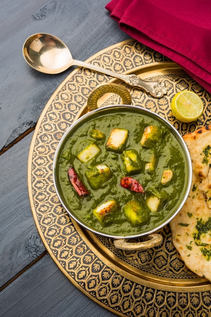 Palak Paneer Curry compuesto de espinacas y requesón, menú popular indio de comida saludable para el almuerzo o la cena, servido en un Karahi con Roti o Chapati sobre un fondo de mal humor. enfoque selectivo