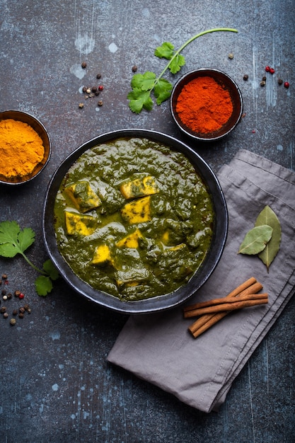 Palak paneer, prato tradicional indiano vegetariano com paneer de queijo, purê de espinafre e especiarias. Caril indiano de paneer verde em tigela de cerâmica rústica sobre fundo de concreto, vista superior