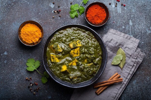 Palak Paneer, traditionelles vegetarisches indisches Gericht mit Käsepaneer, püriertem Spinat und Gewürzen. Indisches grünes Paneer-Curry in rustikaler Keramikschale auf Betonhintergrund, Ansicht von oben