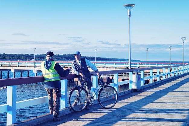 Palanga, Lituânia - 10 de julho de 2017: Homens pescando e uma bicicleta na ponte do mar em Palanga, estância do Mar Báltico, Lituânia