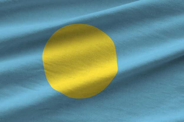 Palau-Flagge mit großen Falten weht aus nächster Nähe unter dem Studiolicht drinnen die offiziellen Symbole und Co