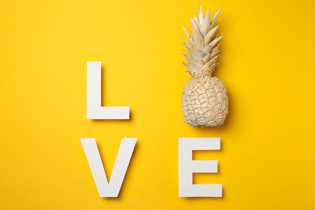 Palavra amor com abacaxi pintado sobre fundo amarelo, espaço para texto