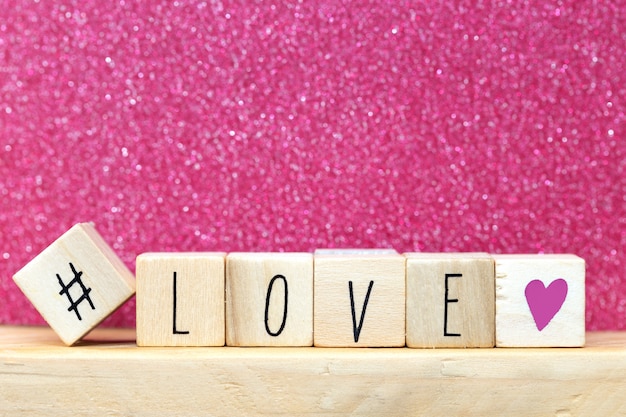 Palavra amor em cubos de madeira com coração rosa e hashtag