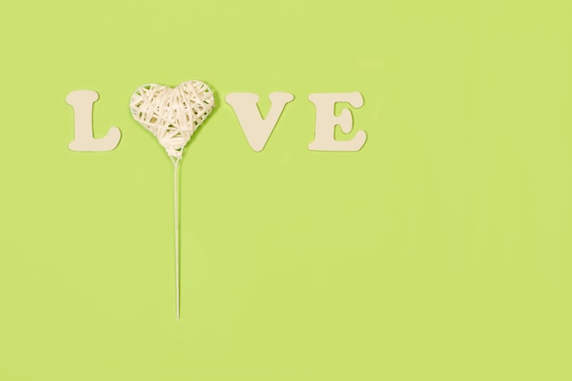 Palavra de amor em letras de madeira e um coração de papel em um fundo verde com espaço de cópia