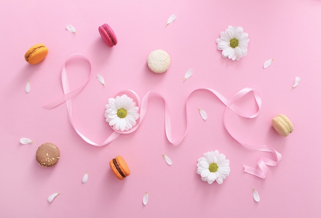 Foto palavra de amor feito de fita rosa com macaroons, flores brancas e pétalas