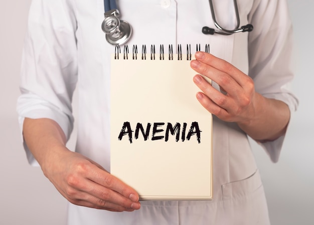 Palavra de anemia no caderno na mão do médico