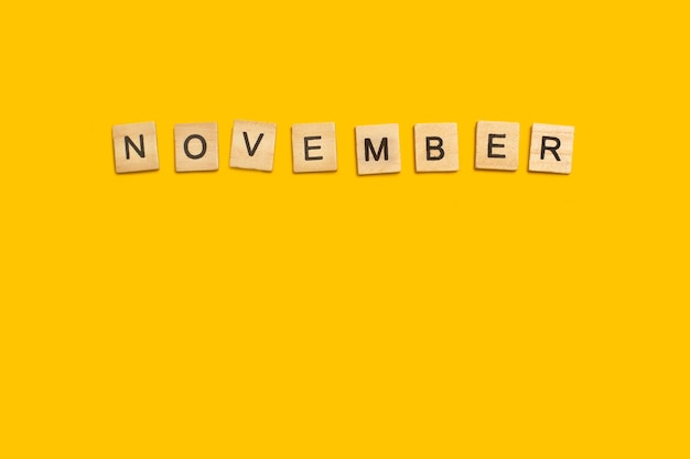 Palavra de novembro feita com blocos de letras de madeira em um fundo amarelo