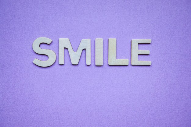 Palavra de sorriso com letras de madeira no fundo roxo