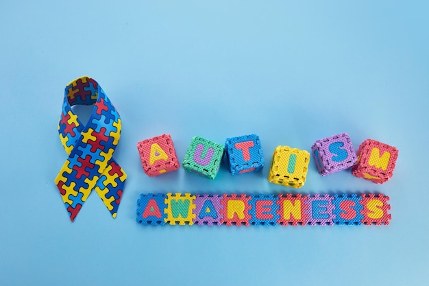 Palavra dia de conscientização do autismo fita de conscientização do autismo e cubos de quebra-cabeça em fundo azul