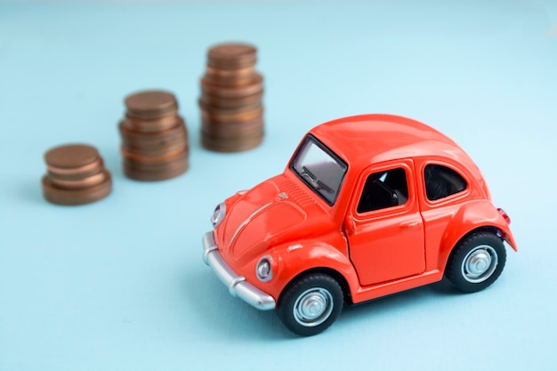 Palavras de seguro de carro, modelo de carro vermelho e moedas sobre fundo azul