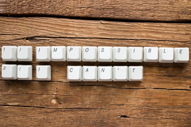 palavras impossíveis e eu não posso das teclas do teclado em fundo de madeira