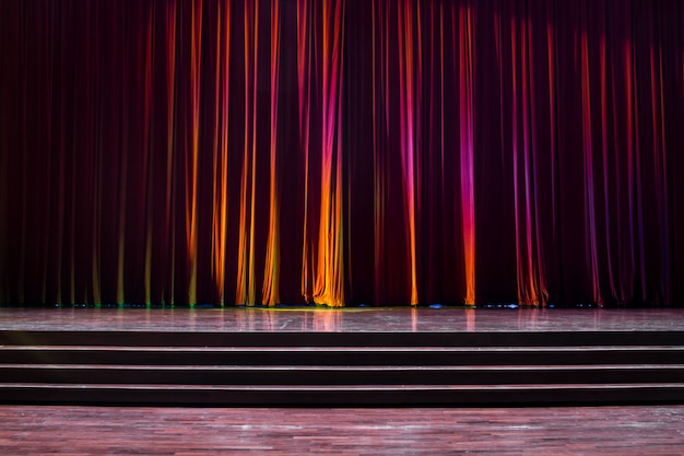 Palco de madeira e cortinas vermelhas.