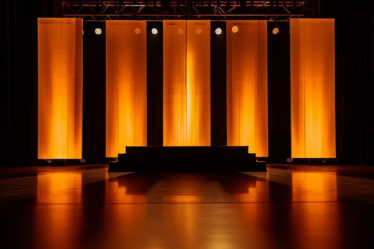 Foto palco moderno com iluminação dramática e painéis de fundo laranja para apresentações