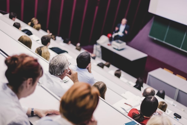 Palestrante na universidade Especialista em saúde dando uma palestra para professores da faculdade de medicina Participantes ouvindo palestra e fazendo anotações