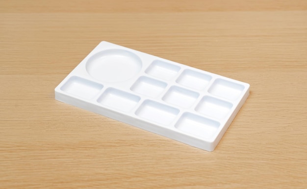 Paleta de acuarela blanca Bandeja de acuarela vacía aislada sobre fondo de madera Paleta blanca