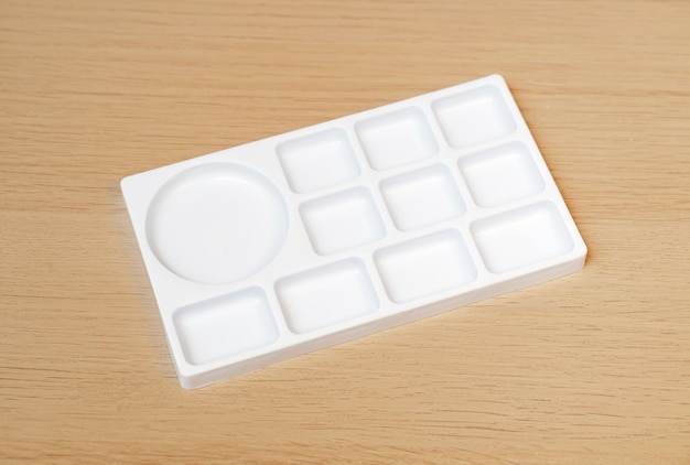 Paleta de acuarela blanca Bandeja de acuarela vacía aislada sobre fondo de madera Paleta de pintura blanca