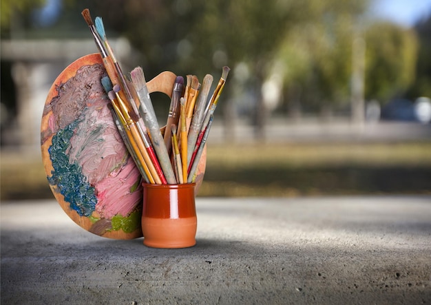 Paleta de artistas, colores y pinceles en el estante.