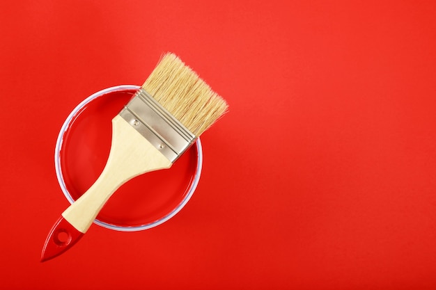 Paleta de colores de latas de pintura con pincel sobre fondo rojo, concepto de renovación del hogar