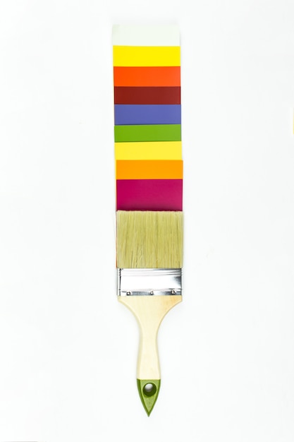 Paleta de colores y pincel con mango de madera sobre fondo blanco.