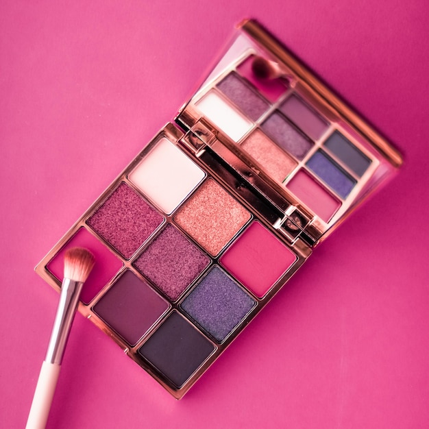 Paleta de sombra e pincel de maquiagem em fundo rosa sombras para os olhos produto de cosméticos como promoção de marca de beleza de luxo e design de blog de moda de férias