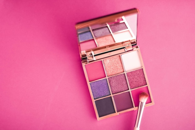 Paleta de sombra e pincel de maquiagem em fundo rosa sombras para os olhos produto de cosméticos como promoção de marca de beleza de luxo e design de blog de moda de férias