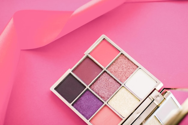 Paleta de sombra e pincel de maquiagem em fundo rosa sombras para os olhos produto de cosméticos para promoção de marca de beleza de luxo e design de blog de moda de férias