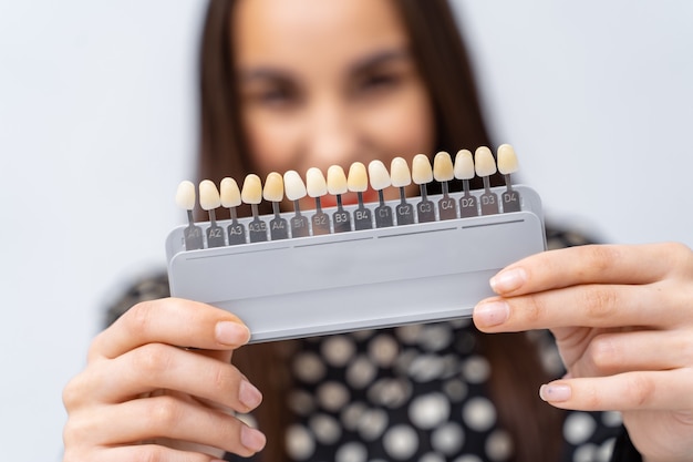 Paleta de dientes de color para blanquear en clínica dental. Chica de fondo borroso. De cerca.