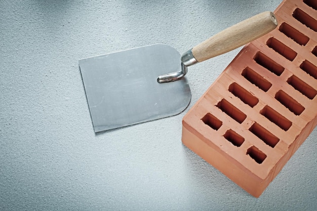 Paleta de enlucido de ladrillos rojos sobre fondo de hormigón concepto de albañilería