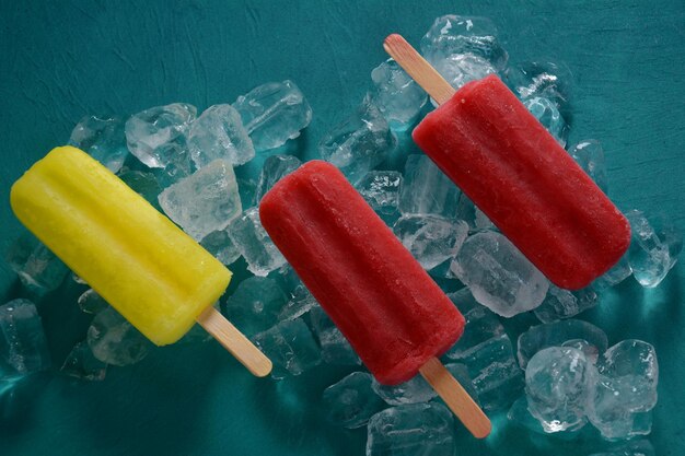 Foto paleta de fresa y paleta de limón sobre fondo azul con hielo