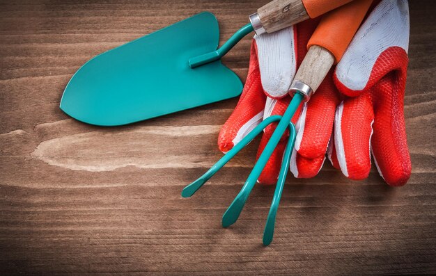 Paleta de guantes protectores y rastrillo sobre tabla de madera