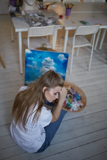 Una paleta de pinturas en manos de una niña.