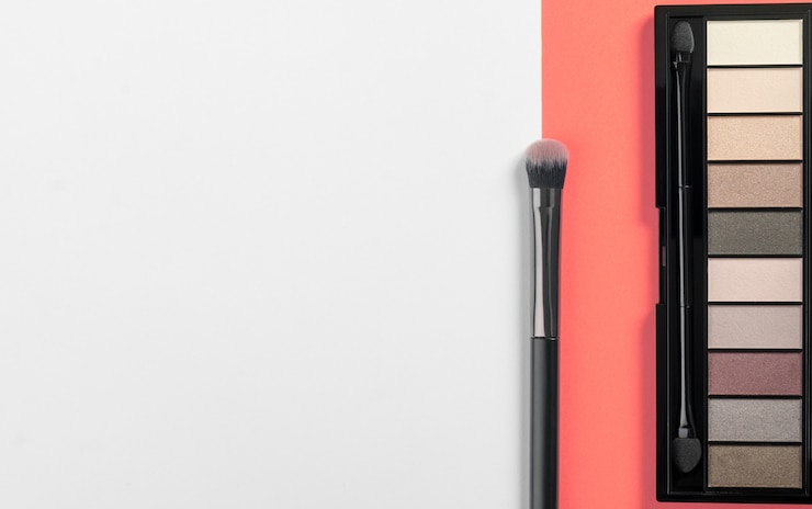 Foto paleta de polvo de sombra de ojos y pincel sobre fondo de color coral con espacio de copia