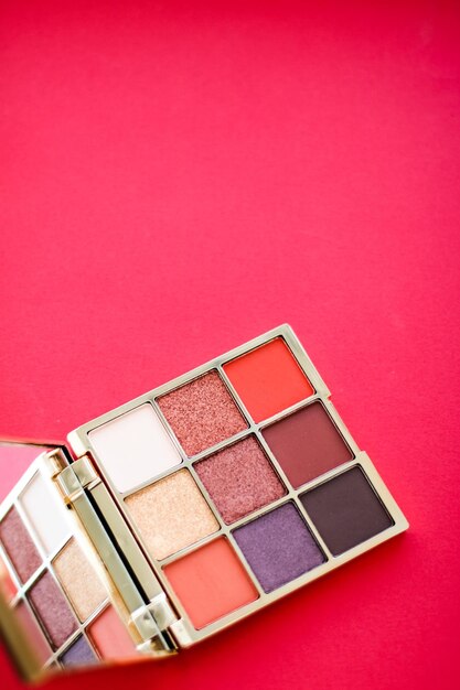 Foto paleta de sombras de ojos y pincel de maquillaje sobre fondo rojo sombras de ojos productos cosméticos para la promoción de marcas de belleza de lujo y diseño de blogs de moda navideña