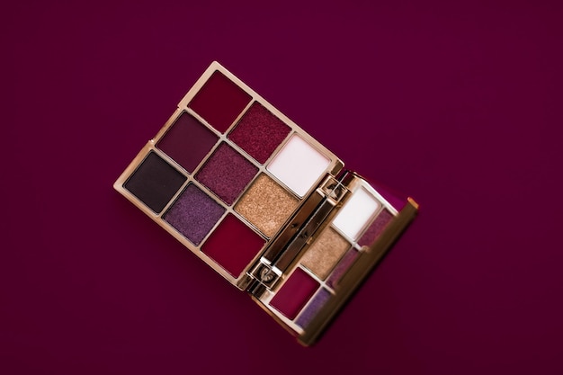 Paleta de sombras de ojos y pincel de maquillaje sobre fondo de vino sombras de ojos productos cosméticos para la promoción de marcas de belleza de lujo y diseño de blogs de moda navideña