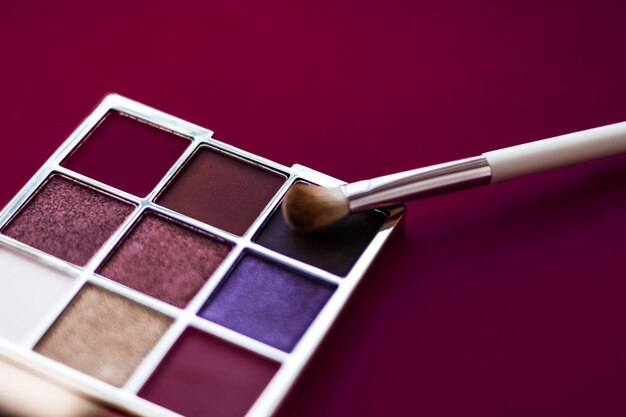 Paleta de sombras de ojos y pincel de maquillaje sobre fondo de vino sombras de ojos productos cosméticos para la promoción de marcas de belleza de lujo y diseño de blogs de moda navideña