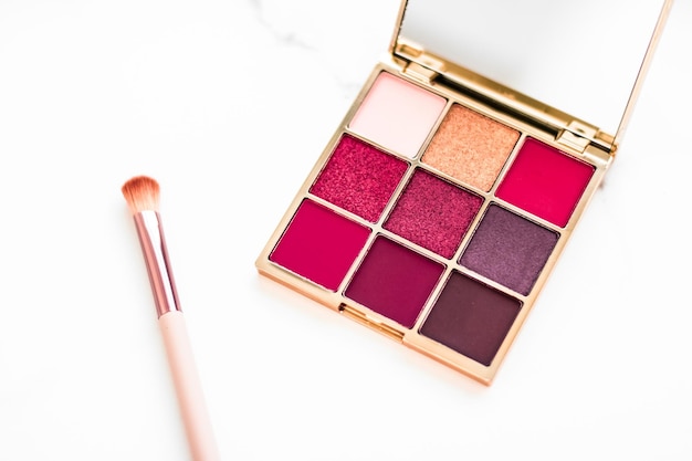 Paleta de sombras de ojos sobre maquillaje de fondo de mármol y productos cosméticos para la promoción de venta de marcas de belleza de lujo y diseño plano de vacaciones