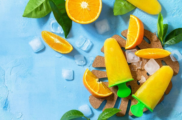 Foto paletas caseras con hielo de fruta de jugo de naranja en una piedra azul vista superior espacio de copia