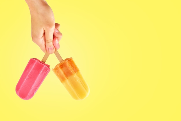 Foto paletas de dos colores en manos de mujer sobre fondo amarillo