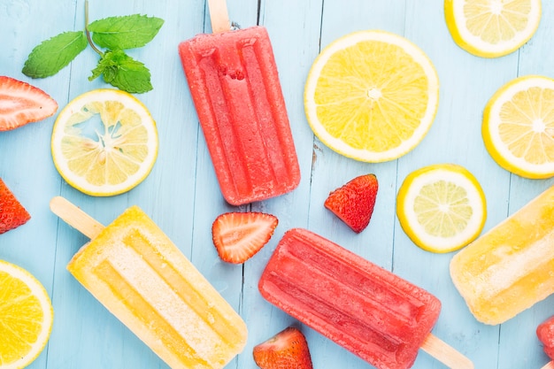 Foto paletas de frutas enteras saludables con bayas fresa naranja dragon fruit sobre mesa de madera vintage