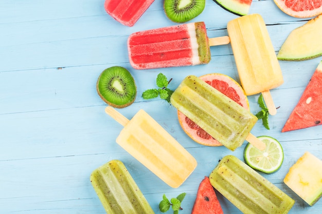 Paletas de frutas enteras saludables con bayas Kiwi melón sandía en mesa de madera vintage