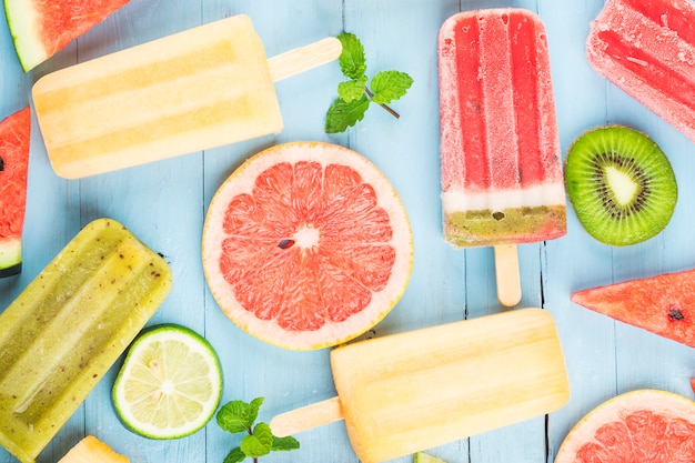 Paletas de frutas enteras saludables con bayas Kiwi melón sandía en mesa de madera vintage