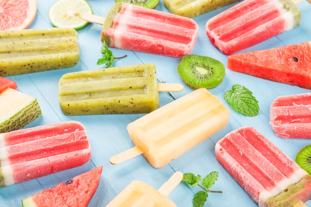 Paletas de frutas enteras saludables con bayas Kiwi melón sandía en mesa de madera vintage