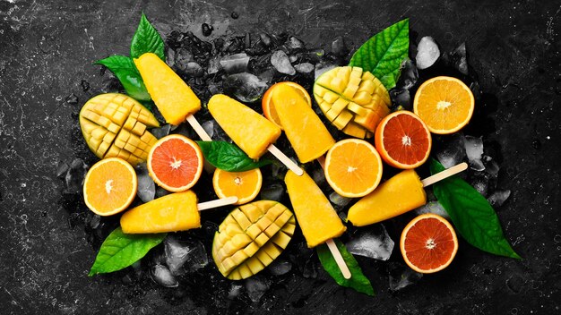 Paletas de frutas tropicales sobre hielo Dulces de frutas de verano frío Sobre un fondo de piedra negra Vista superior